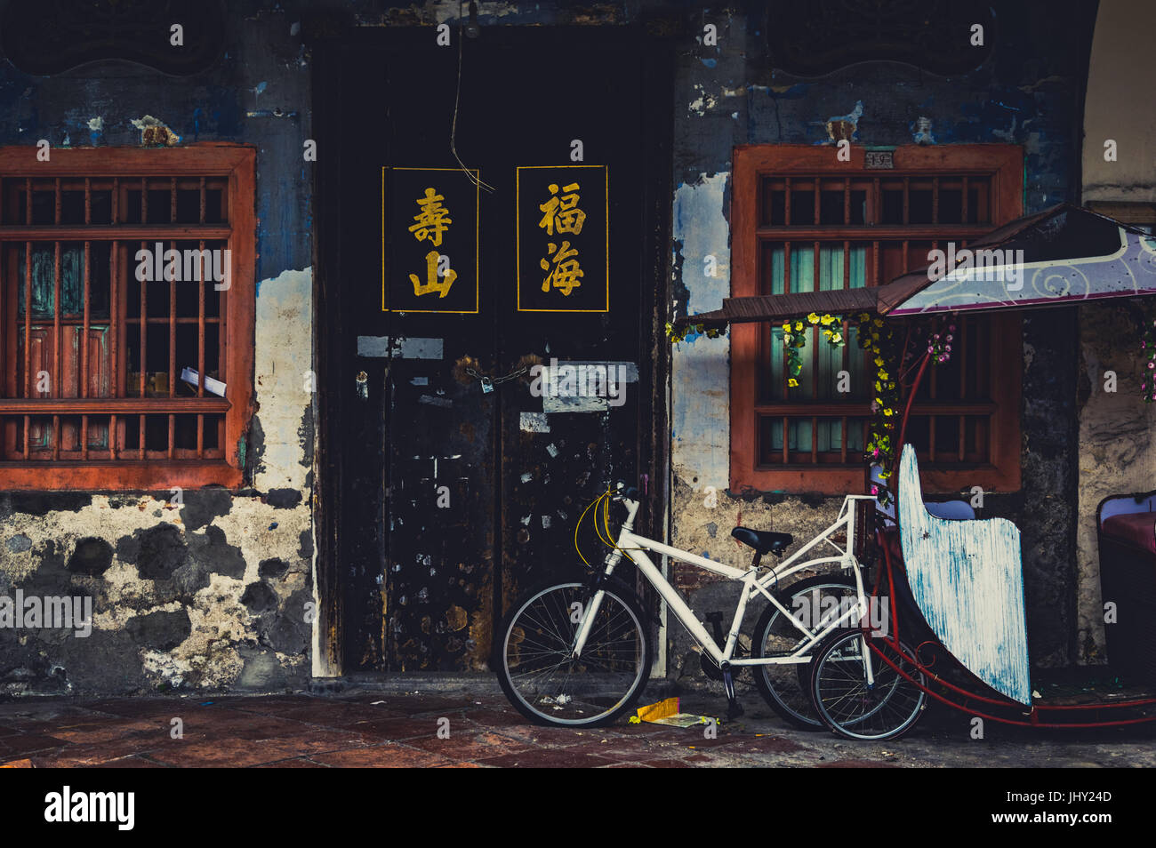 Un vieux cyclo s'appuie contre un mur délabré à Penang, Malaisie Banque D'Images