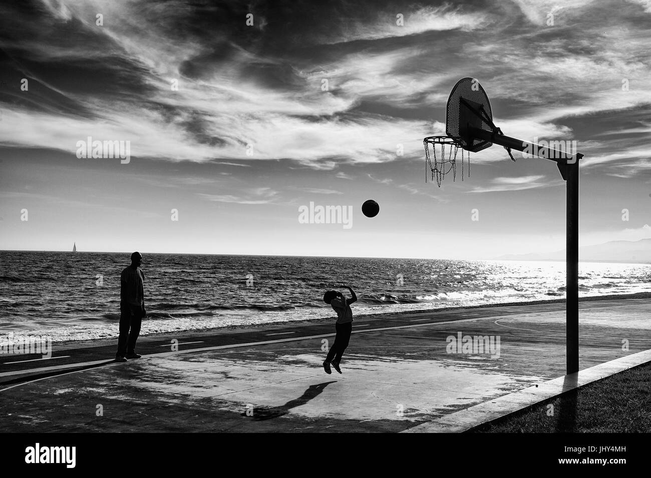 Père de regarder son petit garçon essaie de lancer une balle jusqu'à la corbeille à Cambrils, Espagne Banque D'Images