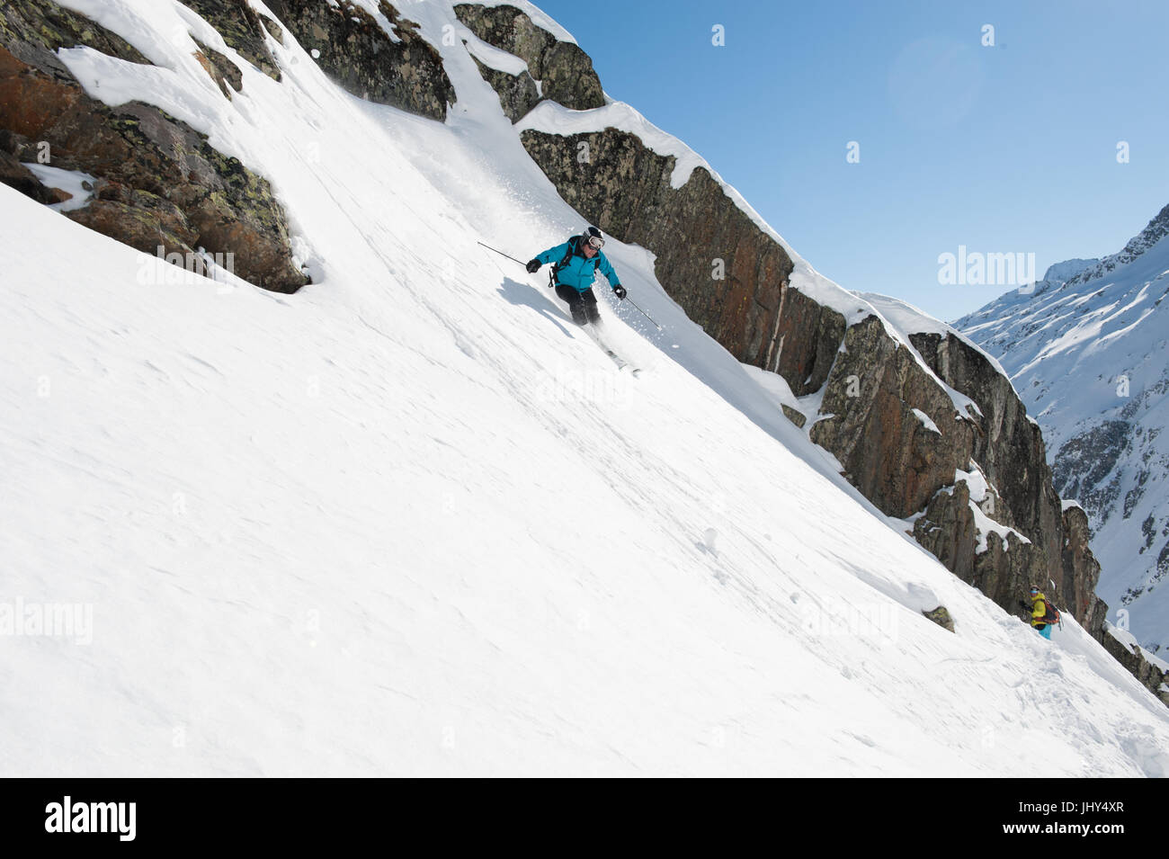 Croisière sur un skieur slop de poudre le long d'une ligne de rochers Banque D'Images