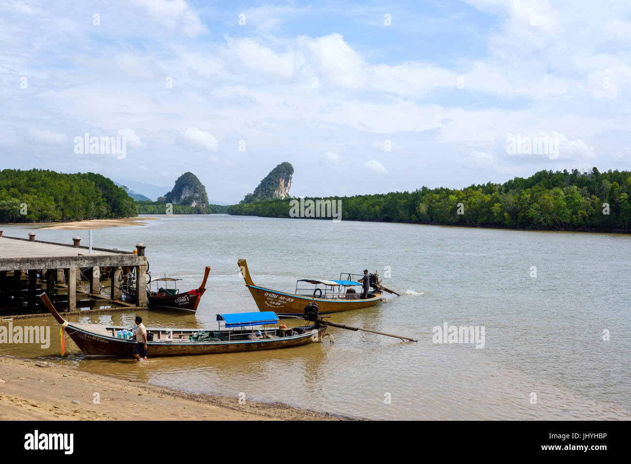 Longtail thailandais bateaux amarrés à Pak Nam Pier, de la rivière de Krabi, avec célèbre Khao Khanab Nam affleurements calcaires dans la distance, la ville de Krabi, Thaïlande. Banque D'Images