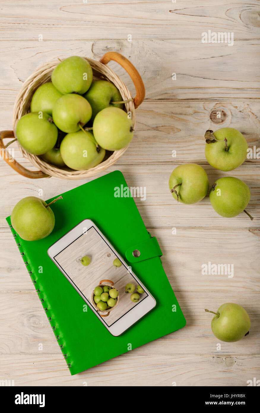 La pomme verte dans un panier, vert et blanc téléphone portable sur un fond en bois clair. Focus sélectif. Banque D'Images
