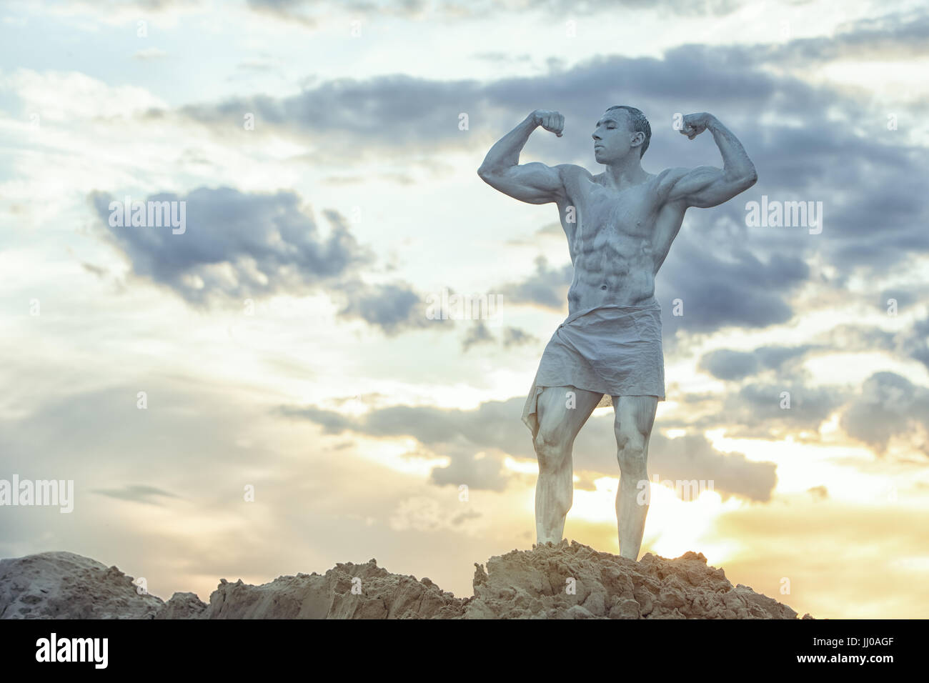 Statue de l'homme vivant dans le contexte de l'ciel du soir. Il a de gros muscles. Banque D'Images