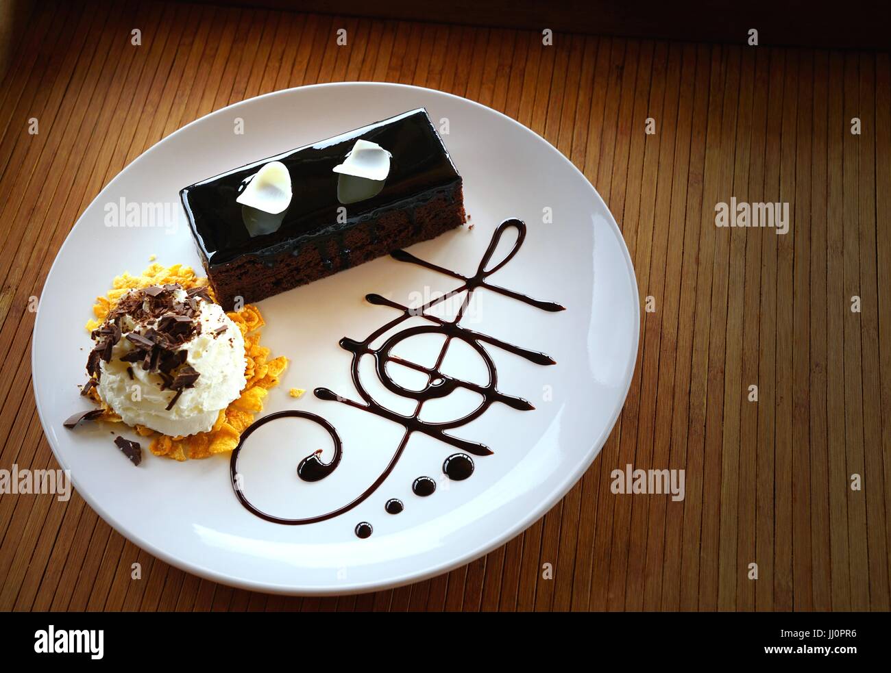 Chocolat Noir Delicieux Gateau Decore Avec Des Copeaux De Chocolat Blanc Coupe Creme Fouettee Et De Chocolat En Forme De Note De Musique Plaque Blanche Sur Table En Bois Photo Stock