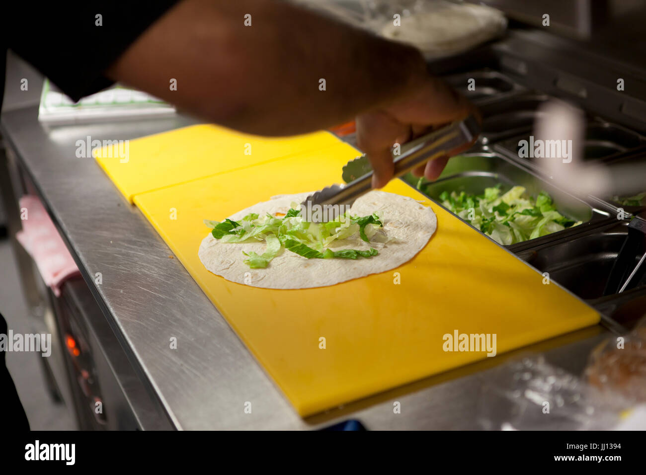 Un membre du personnel prépare un Wrap au poulet grillé dans un KFC en Angleterre, Royaume-Uni. Banque D'Images