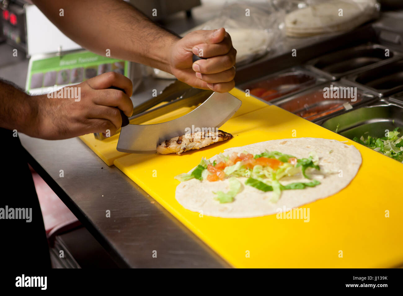 Un membre du personnel prépare un Wrap au poulet grillé dans un KFC en Angleterre, Royaume-Uni. Banque D'Images