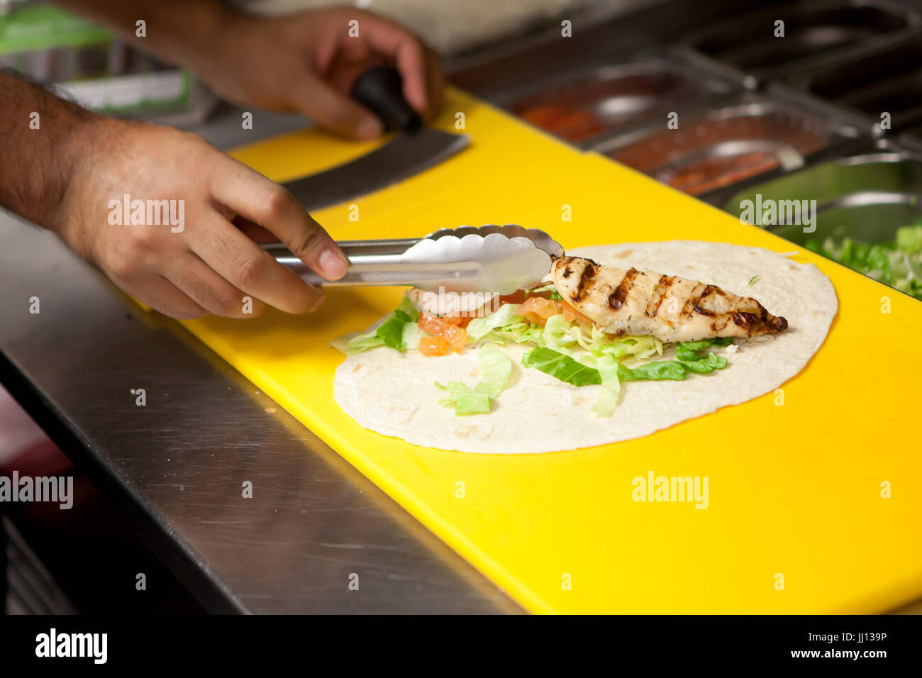 Un membre du personnel prépare un Wrap au poulet grillé dans un KFC en Angleterre, Royaume-Uni. Banque D'Images