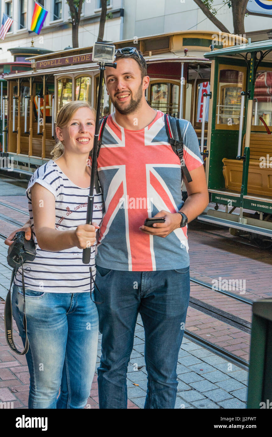 Un jeune couple britannique, en vacances, prendre un en face de l'selfies Powell & Hyde cable car à San Francisco. L'homme porte une chemise qui l'ensemble de shi Banque D'Images