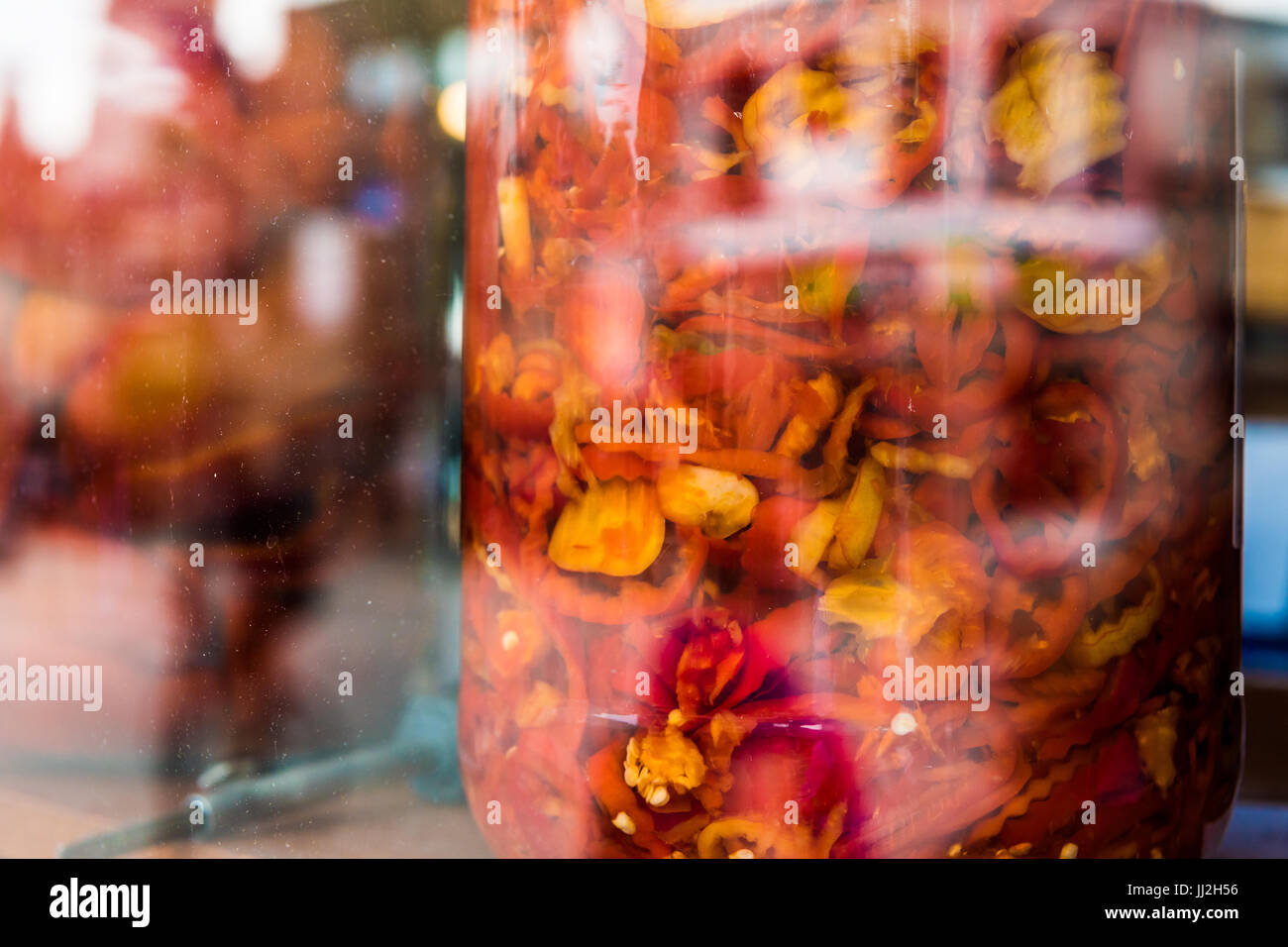 Les poivrons jaunes et rouges marinés dans de grands bols à l'écran derrière le hublot en verre Banque D'Images