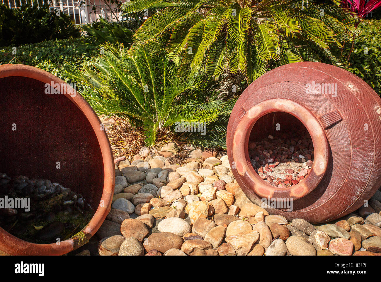 De grands pots en terre cuite reposant sur des pierres dans un jardin Banque D'Images