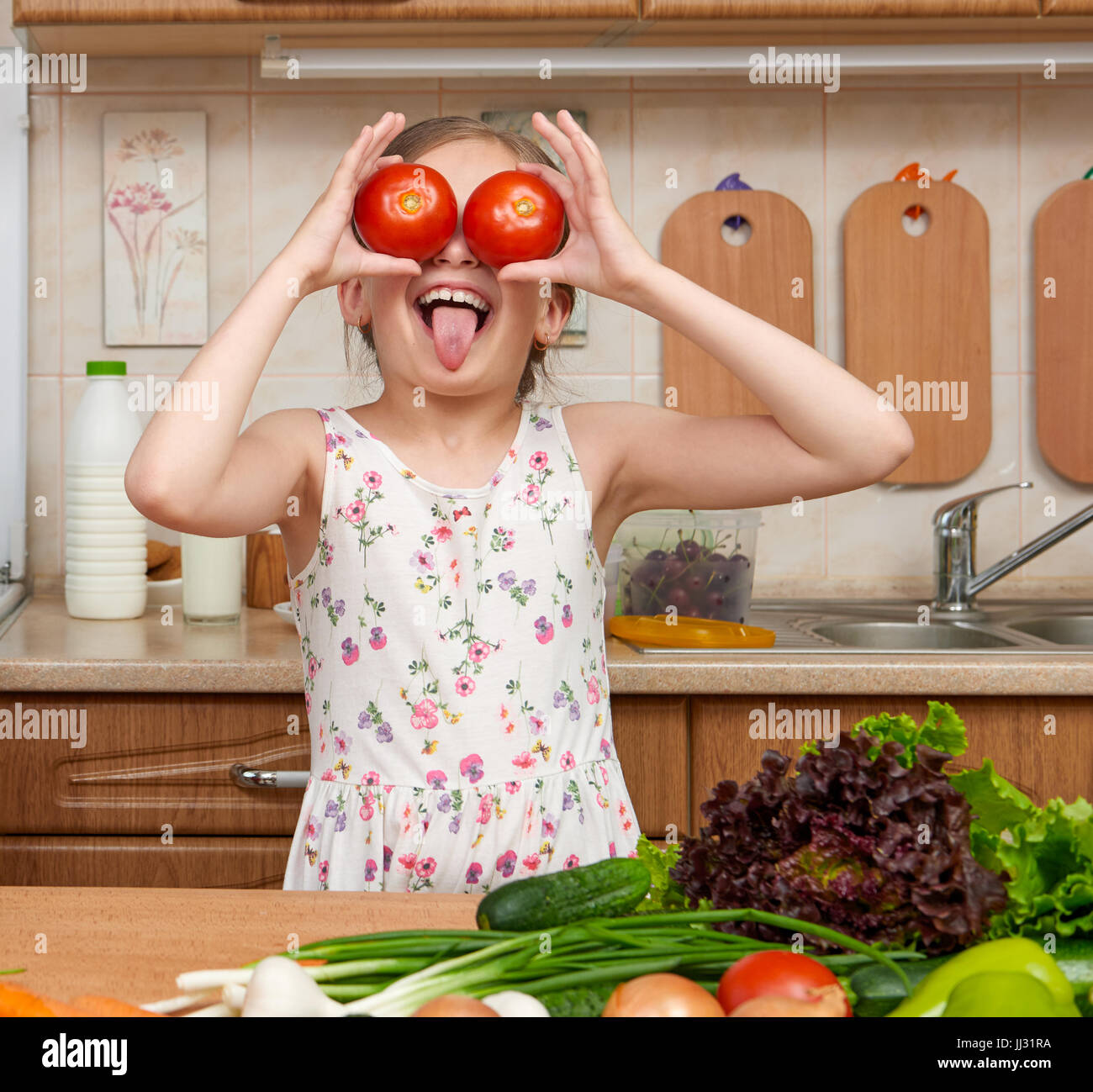 Fille enfant s'amusant avec tomates, regarder à travers comme des jumelles, des fruits et légumes dans la maison cuisine intérieur, concept d'aliments sains Banque D'Images