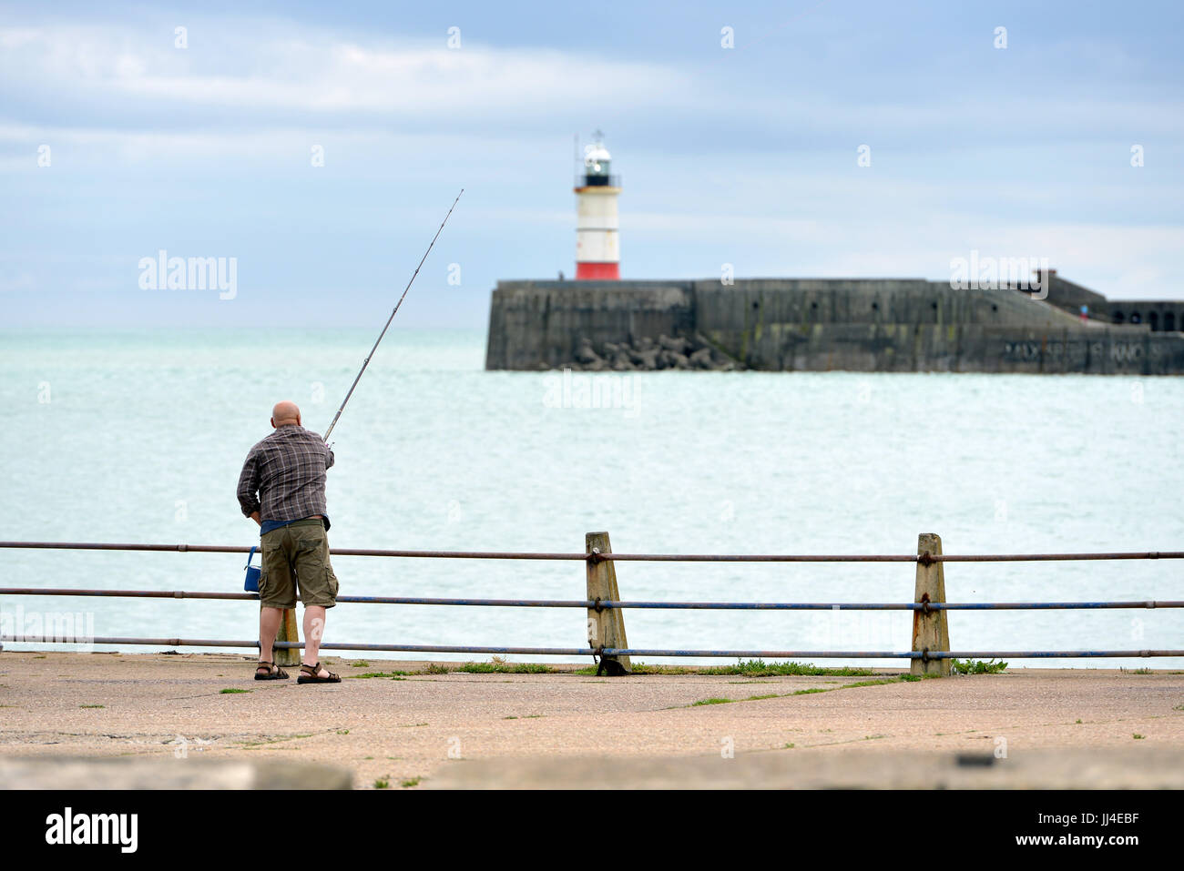 L'homme pêche en mer avec Newhaven phare en arrière-plan Banque D'Images