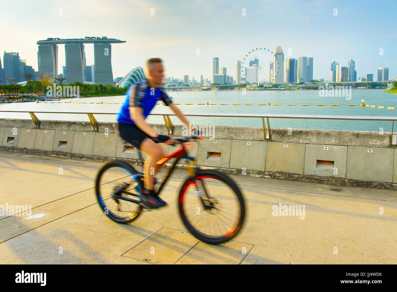 Man riding a bicycle dans la baie de Singapour au coucher du soleil Banque D'Images