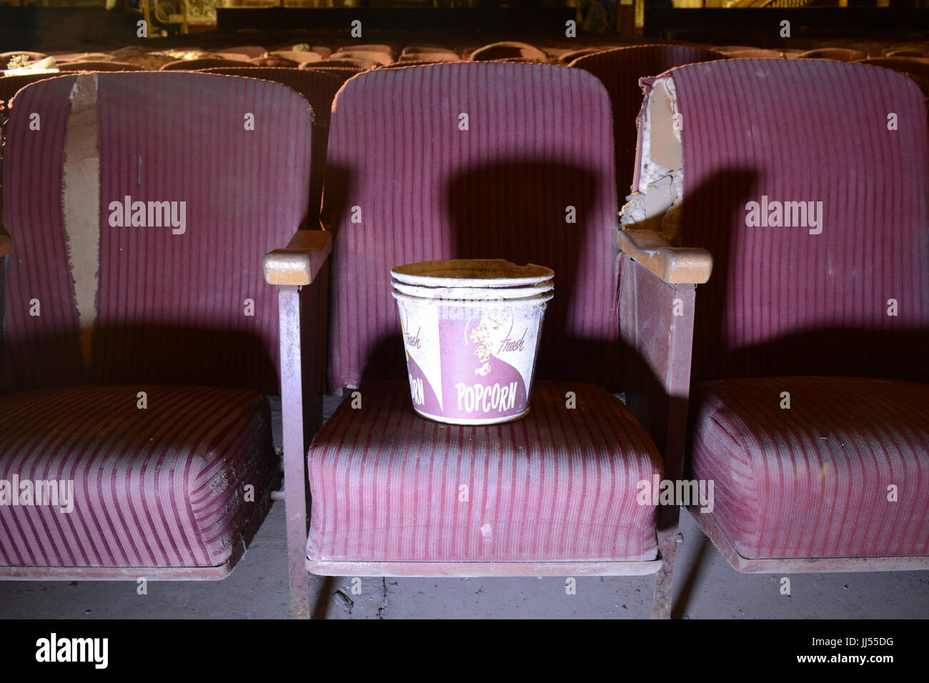 Vintage seau de maîs éclaté sur de vieux sièges déchirés dans un cinéma abandonné Banque D'Images