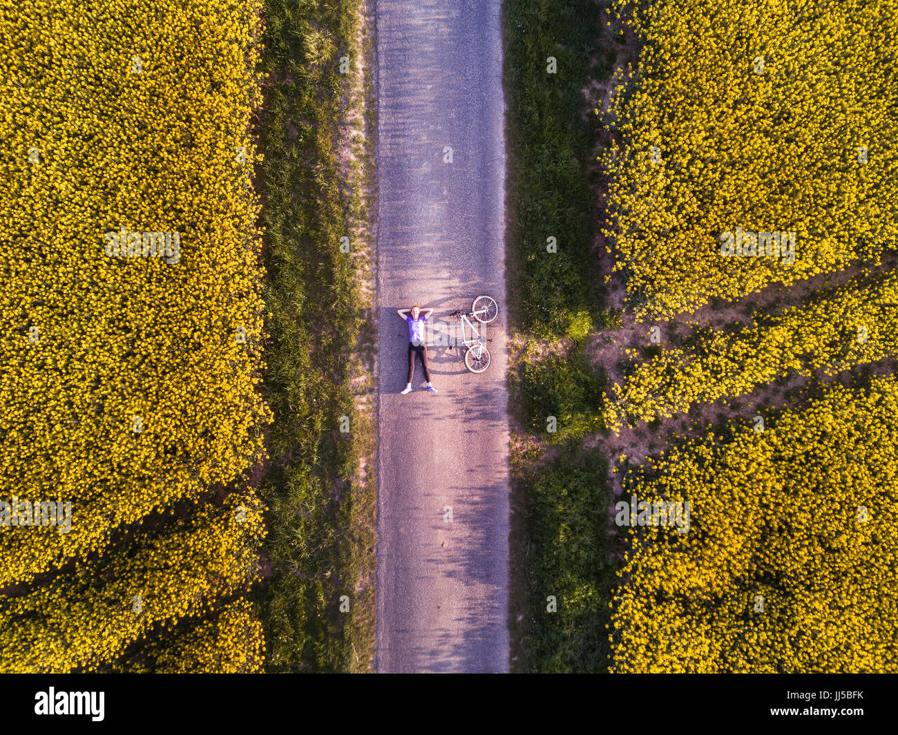 Vue de dessus de la personne d'un vélo sur la route dans les champs, vue aérienne Banque D'Images