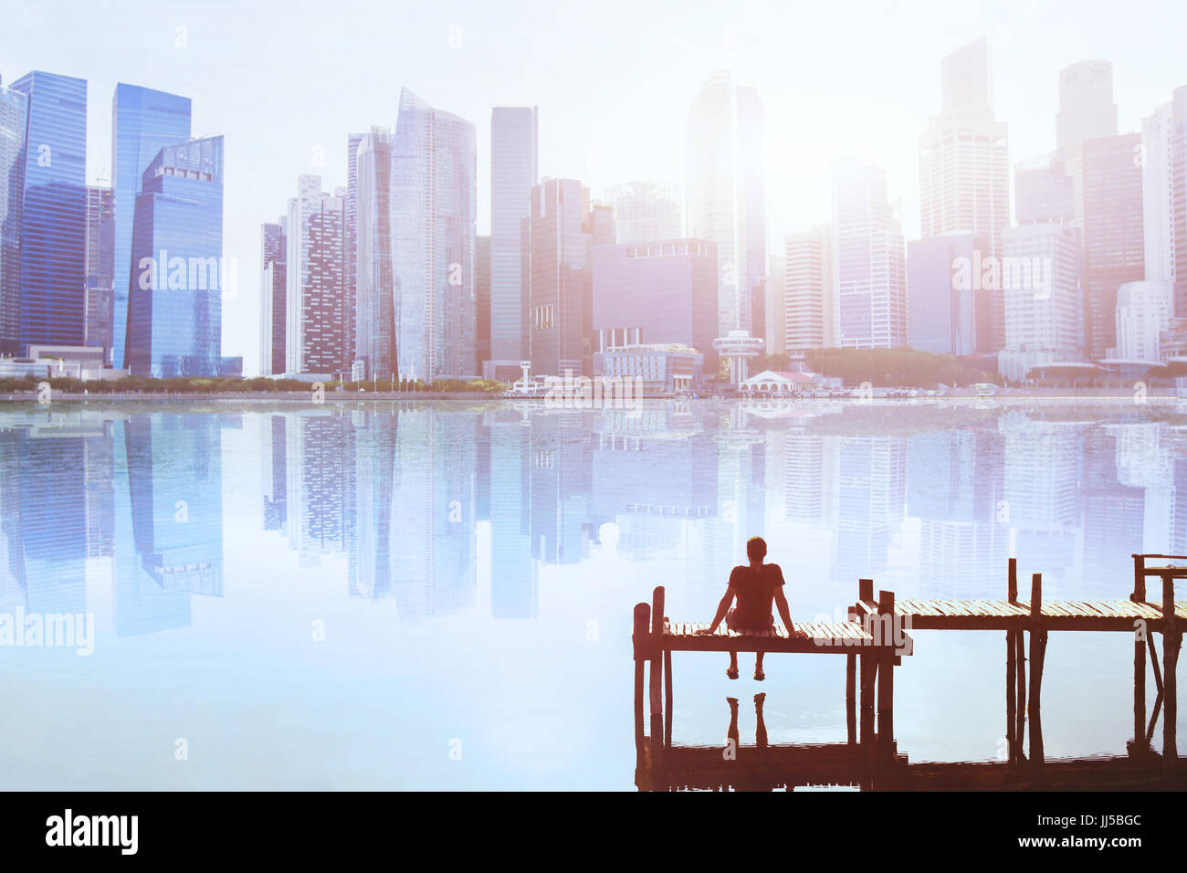 Dream concept, l'homme assis sur la jetée et profiter de la ville moderne vue sur l'horizon Banque D'Images