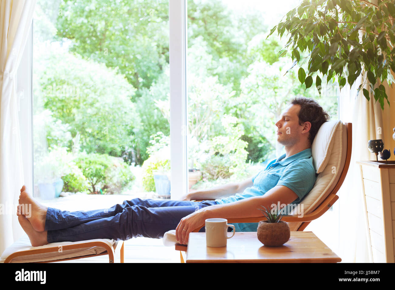 Homme heureux de vous détendre dans une chaise longue à la maison, bien-être, relaxation d'arrière-plan Banque D'Images