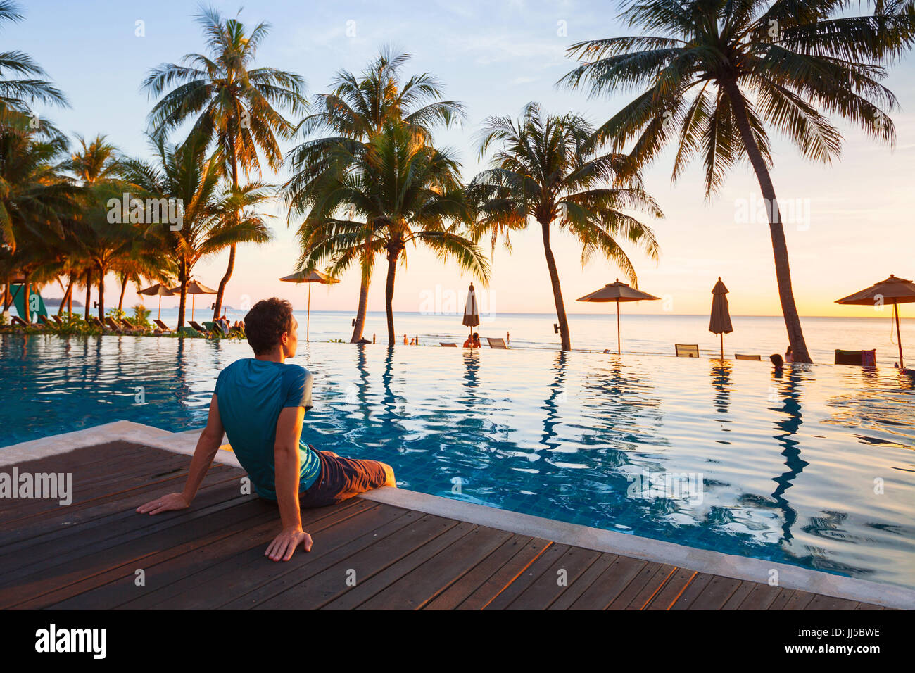 Bonnes vacances à l'hôtel belle plage au coucher du soleil, l'homme assis près de la piscine et se détendre Banque D'Images