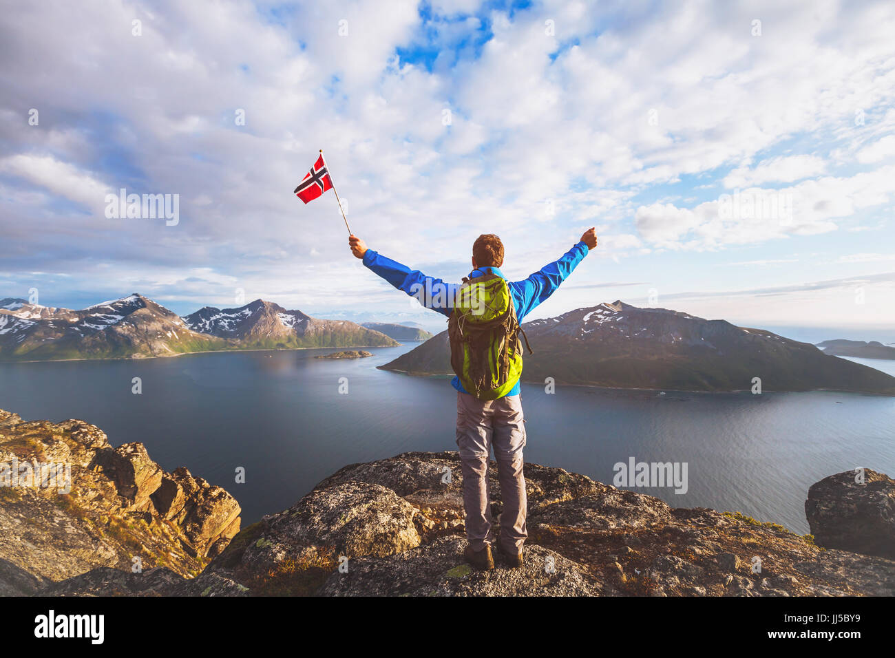 Billet d'avion Norvège, hiker with backpack debout sur le sommet de la montagne et maintenant pavillon norvégien Banque D'Images