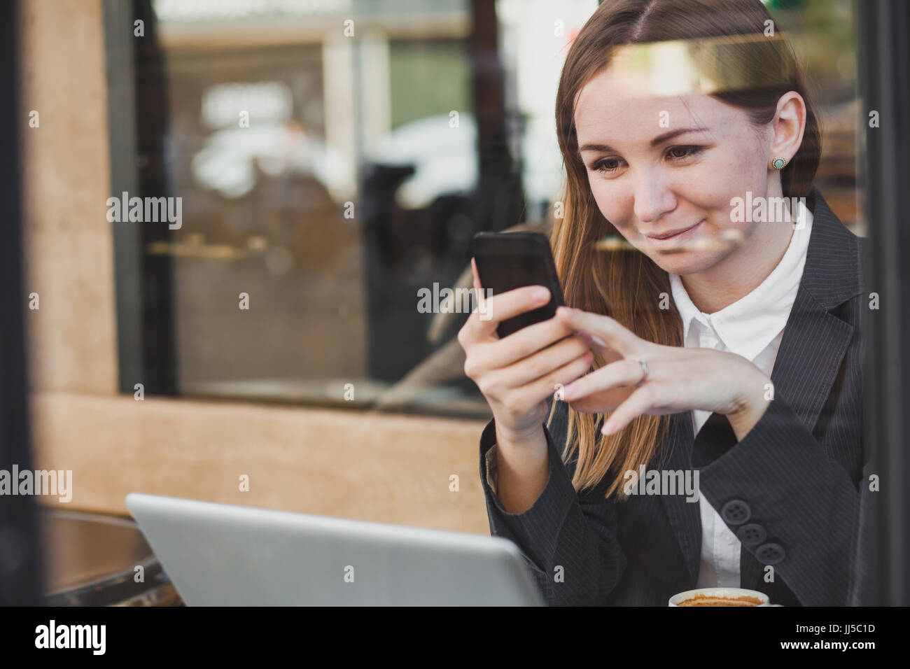 Pretty young woman using smartphone and smiling Banque D'Images