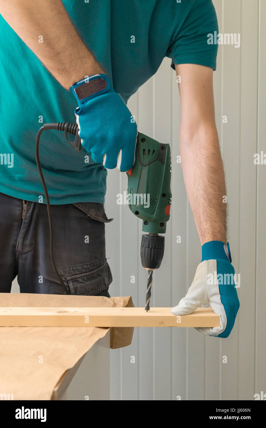 Carpenter handyman en utilisant la perceuse électrique pour faire des trous sur la planche sur la table de l'atelier de menuiserie Banque D'Images