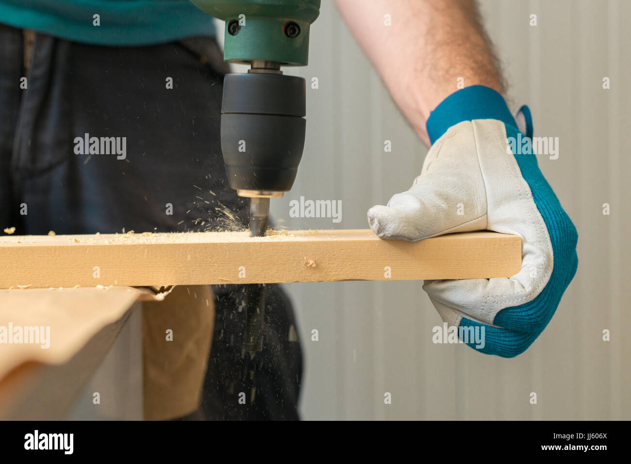 Carpenter handyman en utilisant la perceuse électrique pour faire des trous sur la planche sur la table de l'atelier de menuiserie Banque D'Images