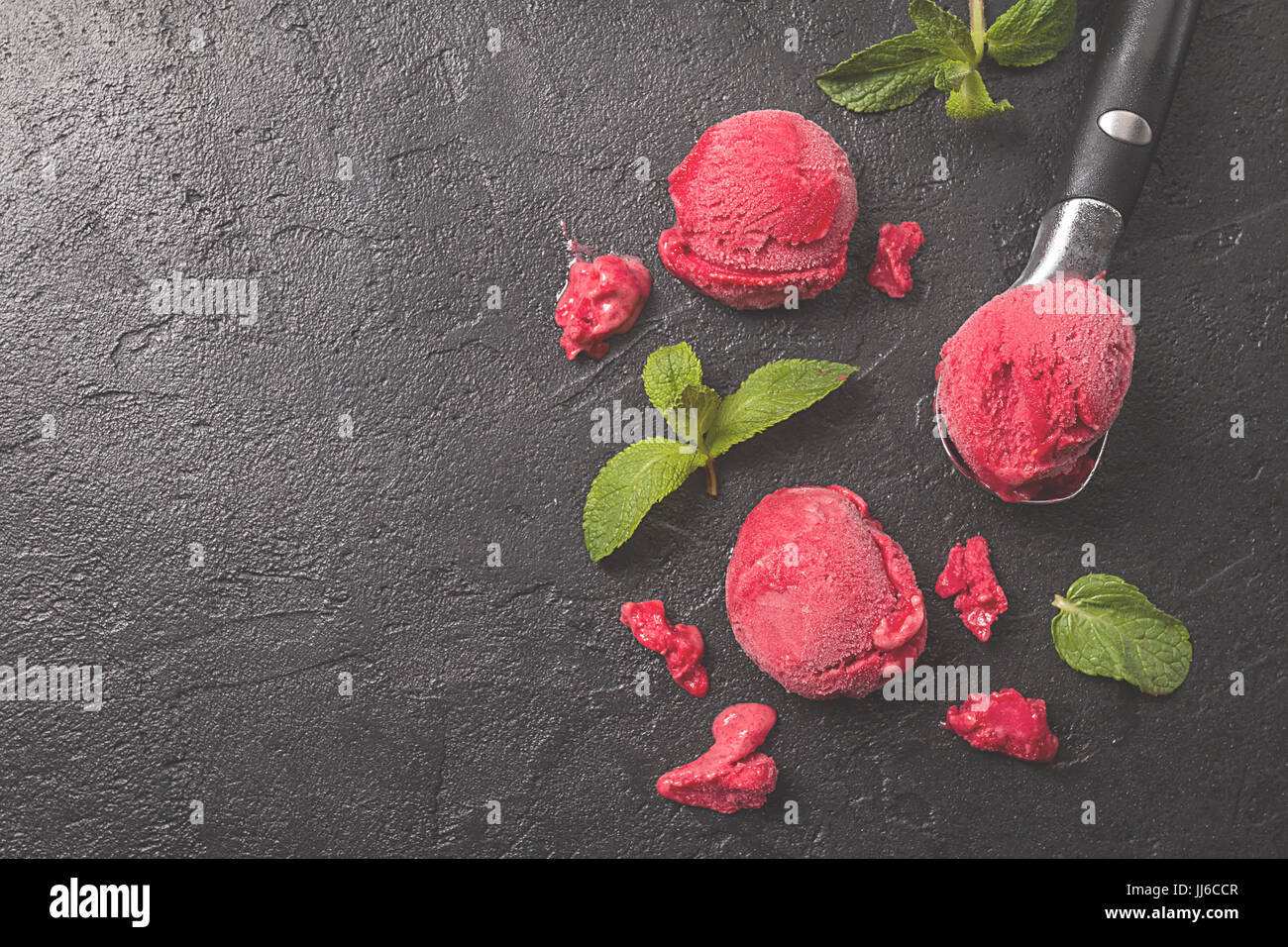 Rouge Framboise crème glace cuillère de crème glacée en boules à la menthe sur fond noir Banque D'Images