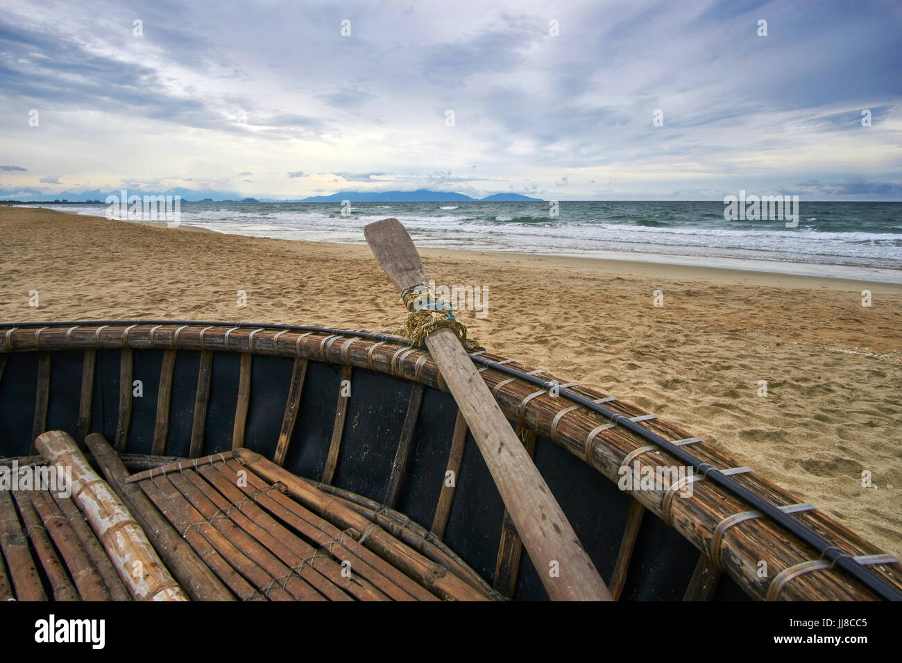 Soirée orageuse à la plage avec des nuages et des vagues. Bateau de coco traditionnel vietnamien à l'avant-plan. Hoi An, la plage de An Bang, Vietnam. Banque D'Images