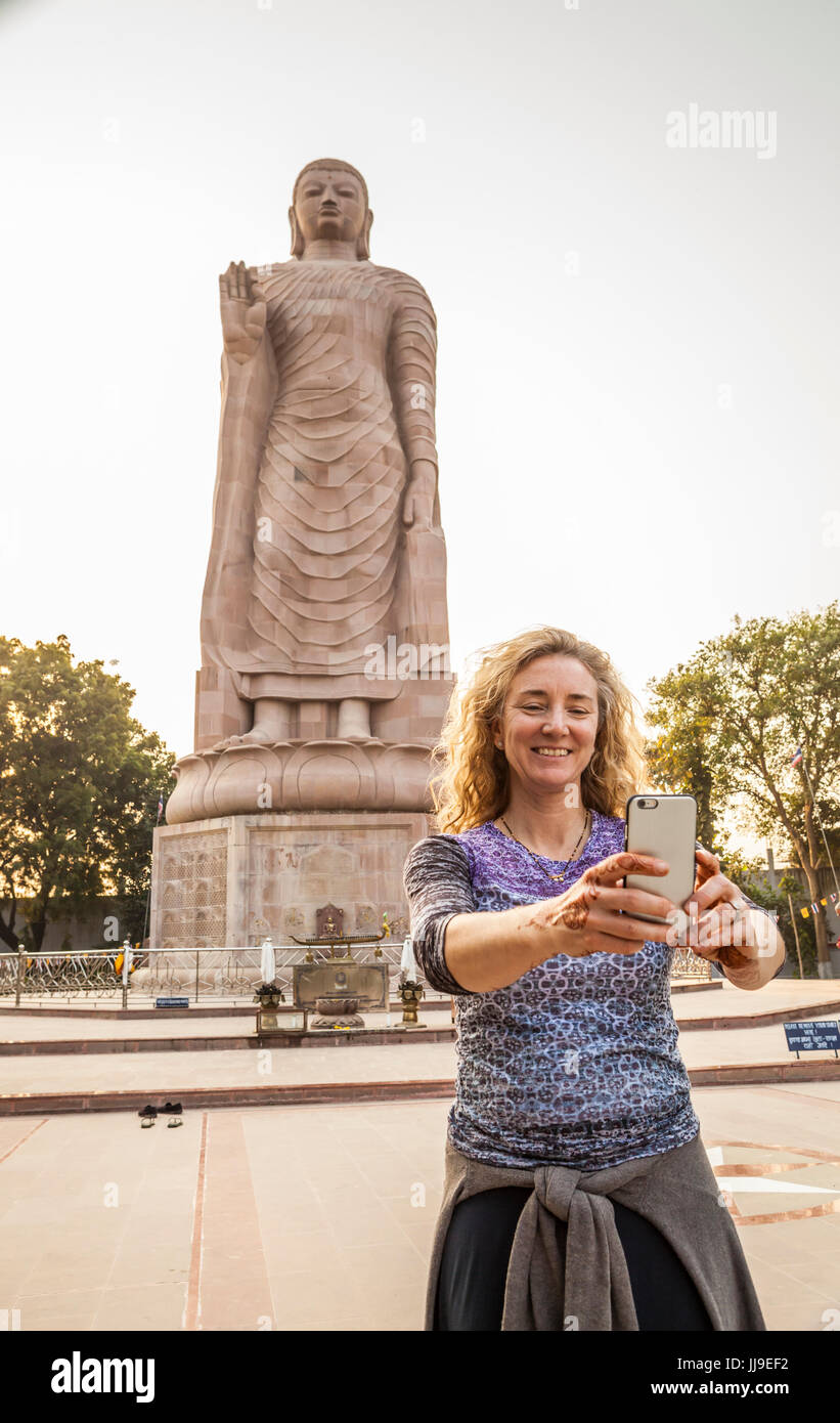Une femme prenant un autoportrait d'elle-même en face de Bouddha Thai Vihar à Sarnath, l'Inde. Banque D'Images