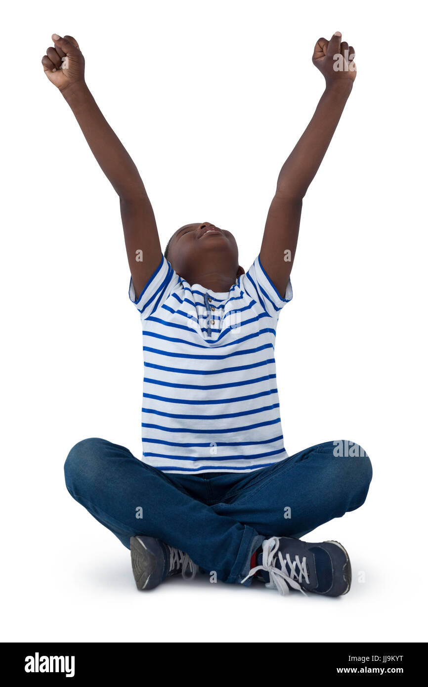 Excited boy sitting on floor against white background Banque D'Images