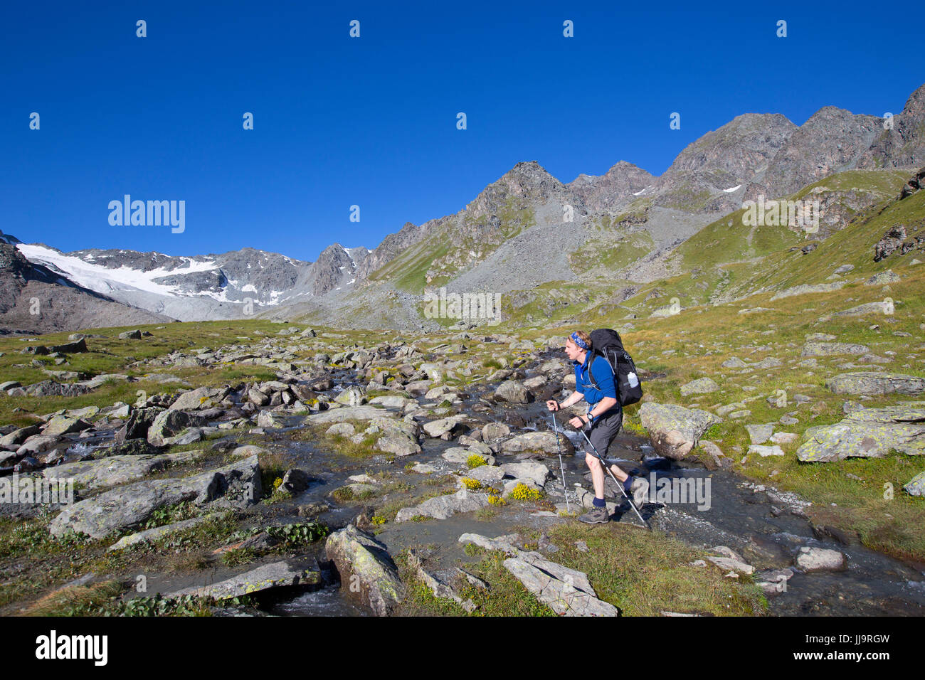 Un randonneur est de marcher près du Lac des Dix dans les Alpes suisses. Le terrain est boueux après le retrait des glaciers. Banque D'Images