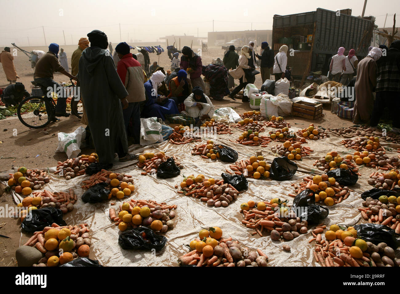 Rue de sable poussiéreux dans la casbah de M'hamid le sud du Maroc. Marché où les carottes, pommes de terre et les oignons sont vendus Banque D'Images