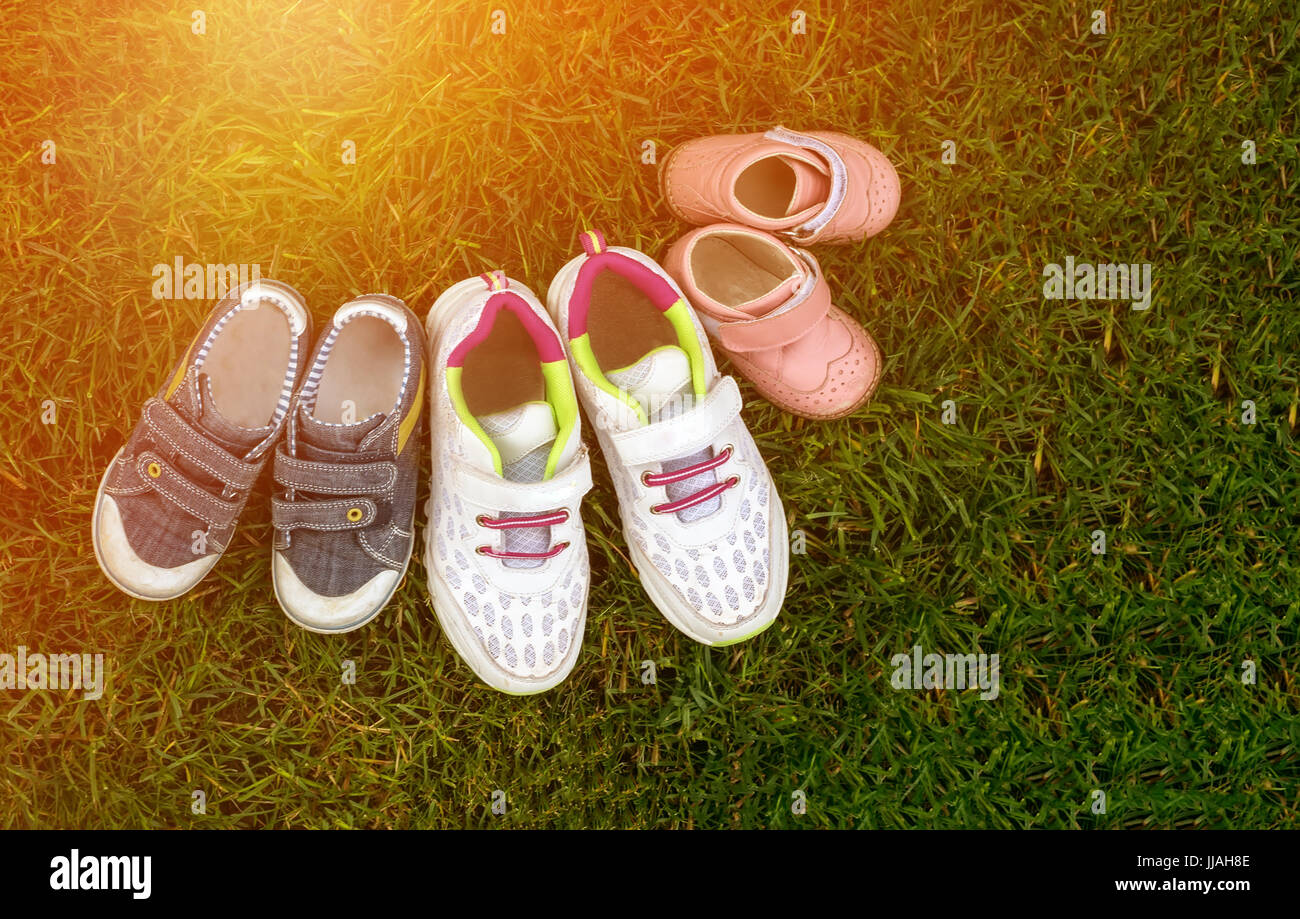 Chaussures bébé trois paires dans l'herbe - un symbole d'enfants dans la famille. Banque D'Images