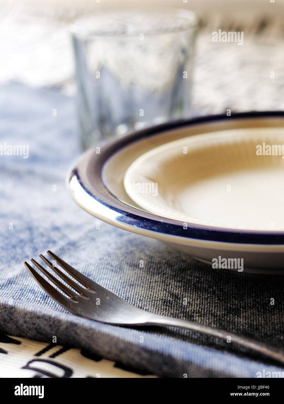 Une table avec une fourchette, bols, et de verre sur une nappe bleue. Banque D'Images