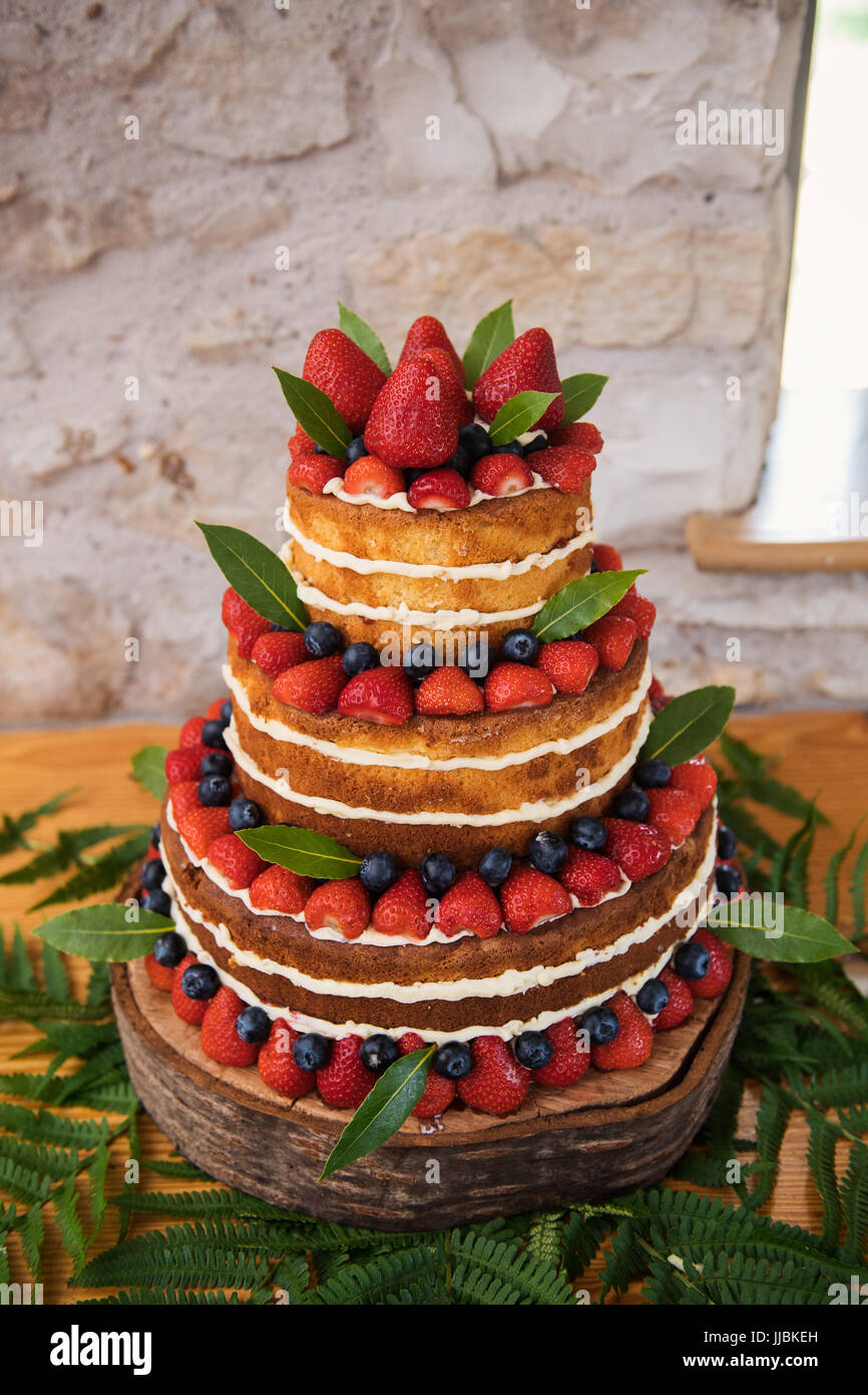 Un gâteau de mariage rustique avec fraises, bleuets, et le givrage, lors d'une réception de mariage Banque D'Images