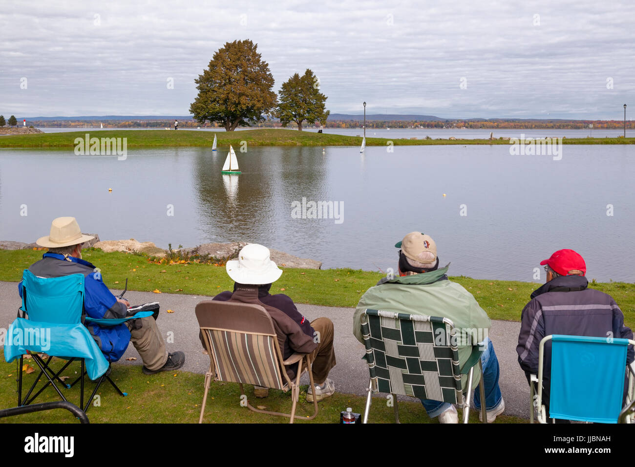Des gens assis dans des chaises à l'aide de bateaux radio-commandés sur un petit étang à Andrew Haydon Park à Ottawa, Ontario, Canada. Banque D'Images