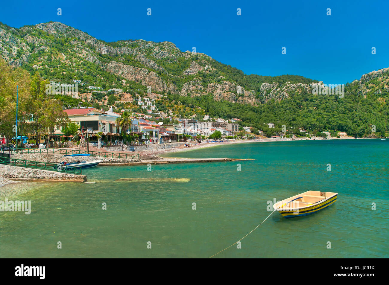 Jaune petit bateau amarré près de city waterfront sur sinny journée avec les montagnes en arrière-plan dans turunc, Marmaris, Turquie Banque D'Images