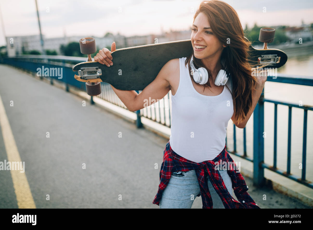 Portrait of beautiful smiling girl skateboard transport Banque D'Images