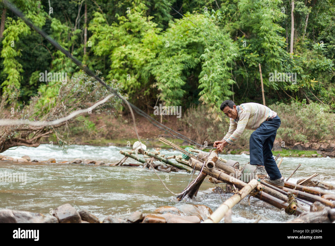Un homme règle le micro-centrales éoliennes dans le flux de la rivière Nam Ou à Ban Sop Kha, le Laos. Les turbines sont utilisées par tous les villages le long de la rivière pour produire de l'électricité, au moins pendant la saison sèche, quand le niveau d'eau est suffisamment bas pour les monter au lit de la rivière. Banque D'Images