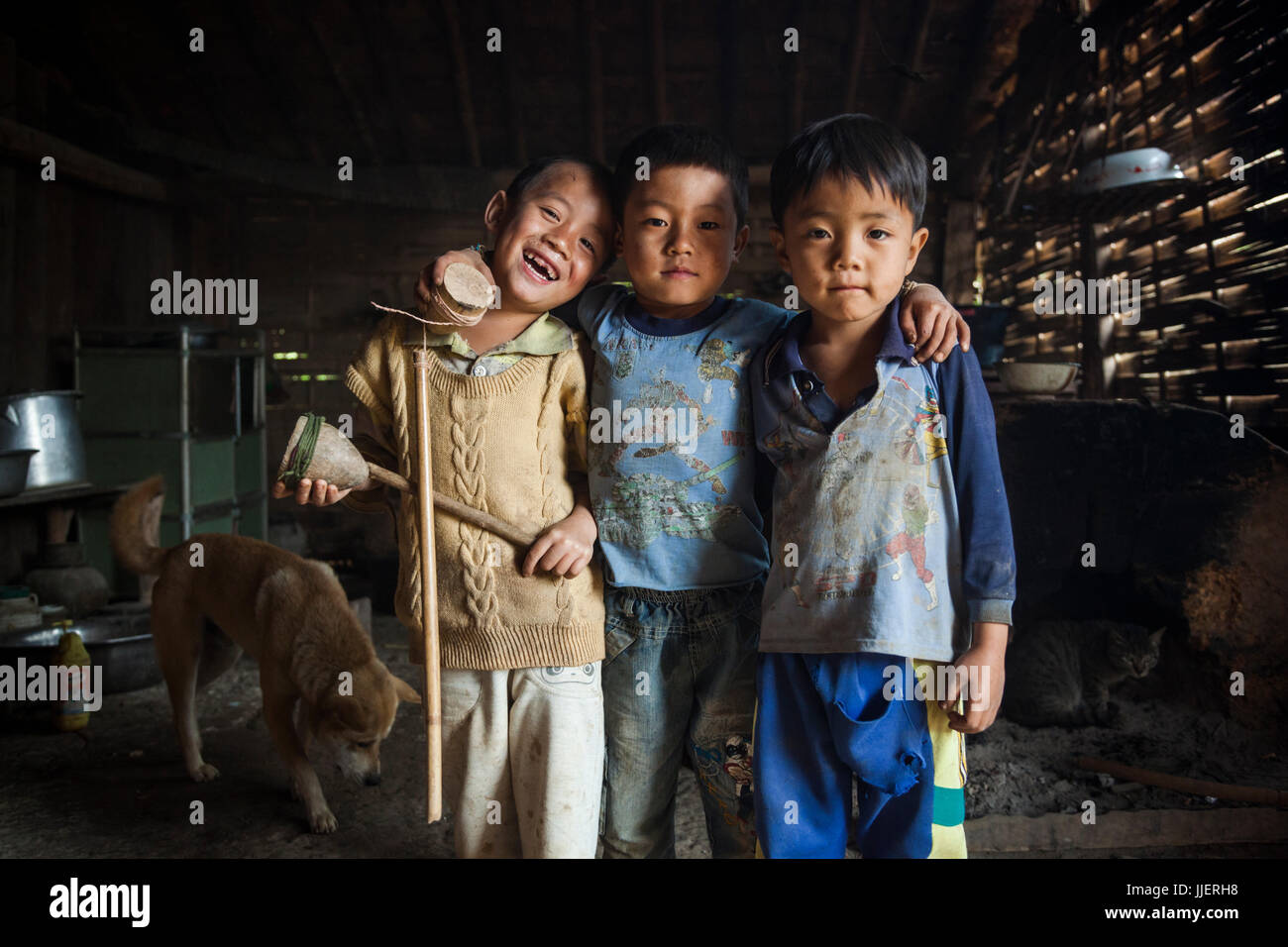 Trois amis, tenant leurs toupies en bois, dans une maison à Ban Sop Kha, le Laos. Banque D'Images
