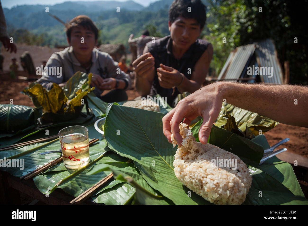 Robert Hahn sert lui-même pour le riz collant pendant le déjeuner sur un site de construction pour une maison neuve à Ban Phak Kung, le Laos. De nombreux membres de la communauté viennent aider et sont a remercié avec un repas. Banque D'Images