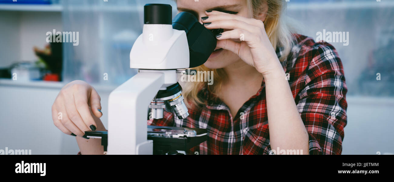 Étudiante en classe de sciences biologiques avec microscope Banque D'Images