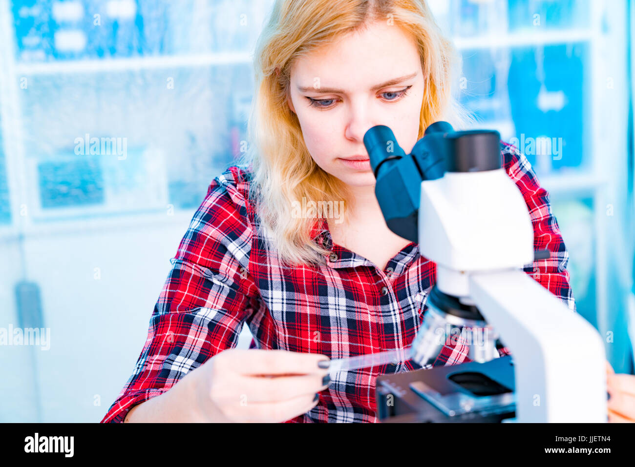 Étudiante en classe de sciences biologiques avec microscope Banque D'Images