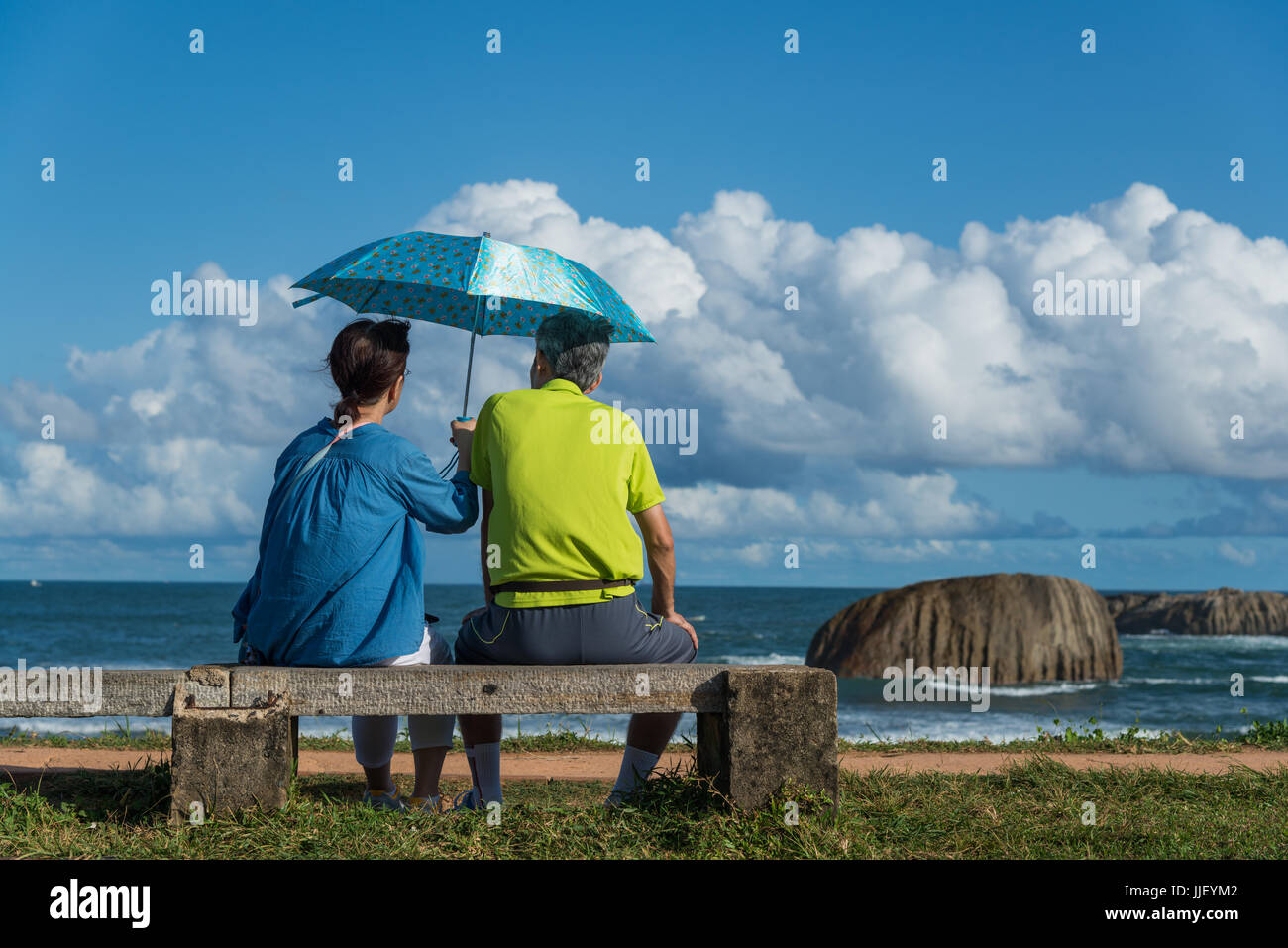 Couple assis sur un banc, tenant un parapluie, Galle, Sri Lanka Banque D'Images