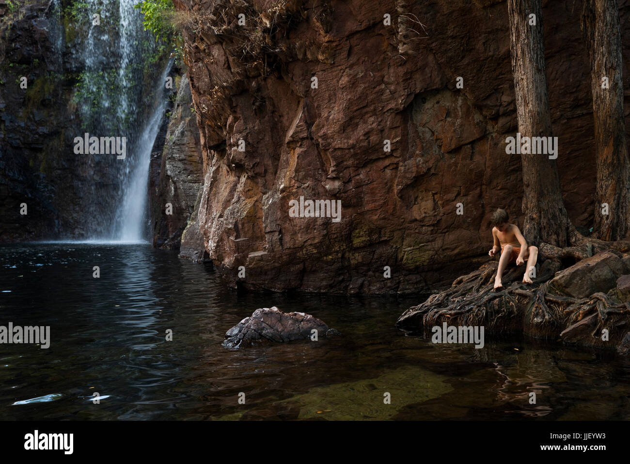 Garçon assis par une cascade, Australie occidentale, Australie Banque D'Images