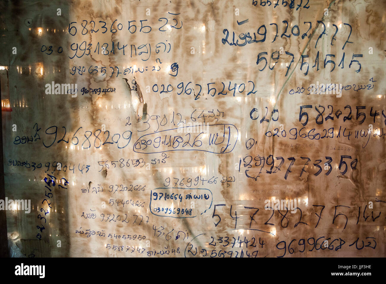 Numéros de téléphone sur le mur d'une maison à Ban Huay Phouk, Laos. Banque D'Images