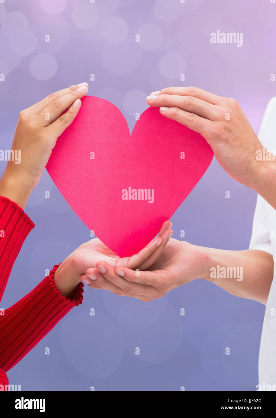 Digital composite of hands holding coeur lumière étincelante avec arrière-plan flou Banque D'Images