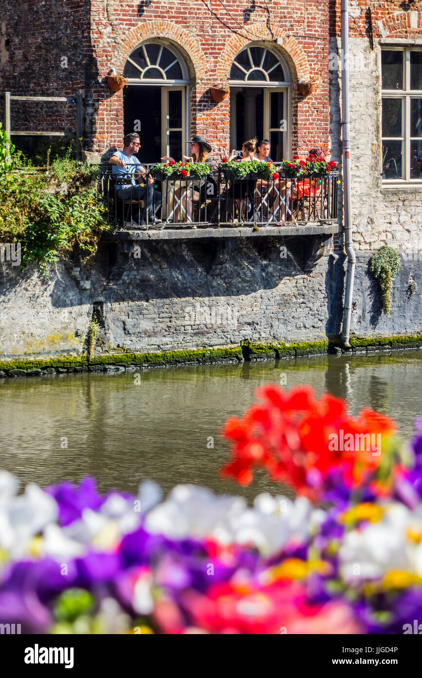 Les touristes assis dehors sur le balcon de restaurant / bar au-dessus de l'eau de la rivière Lys / Lys dans le vieux centre-ville de Gand / Gent, Flandre orientale, Belgique Banque D'Images