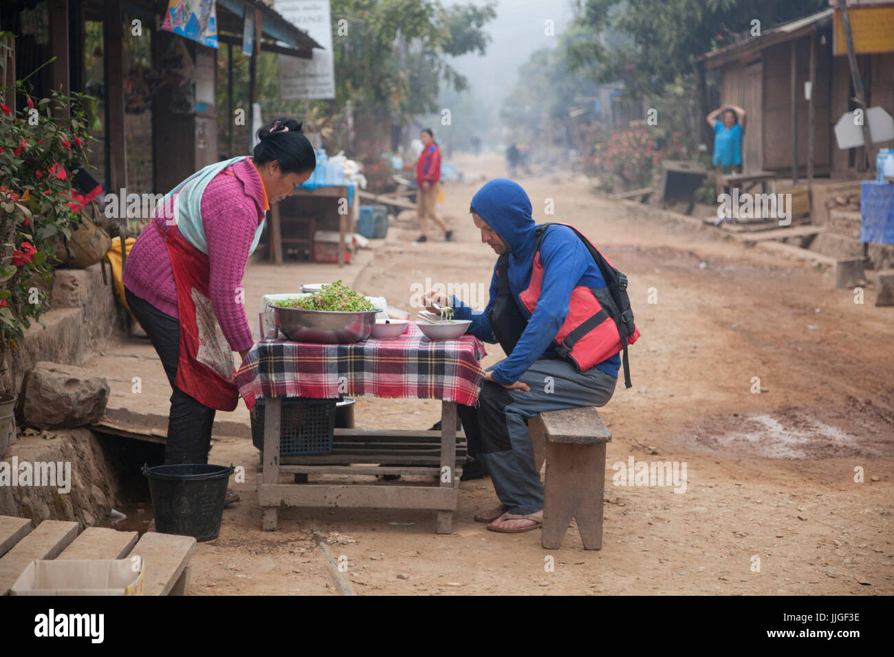 Robert Hahn a soupe de nouilles pour le petit-déjeuner dans la rue principale de Muang Ngoi, Laos. Banque D'Images