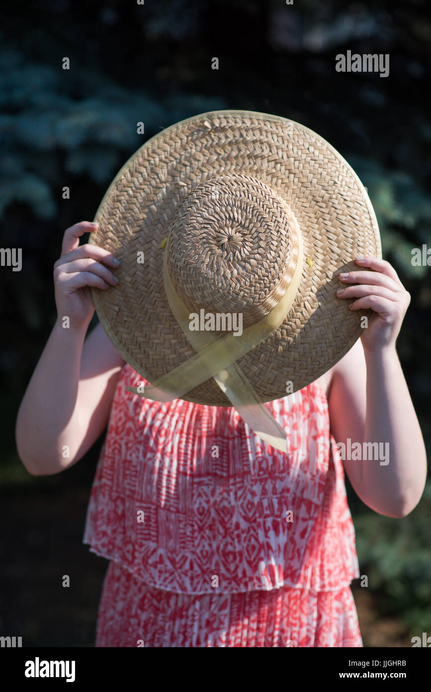 Woman holding hat devant son visage Banque D'Images