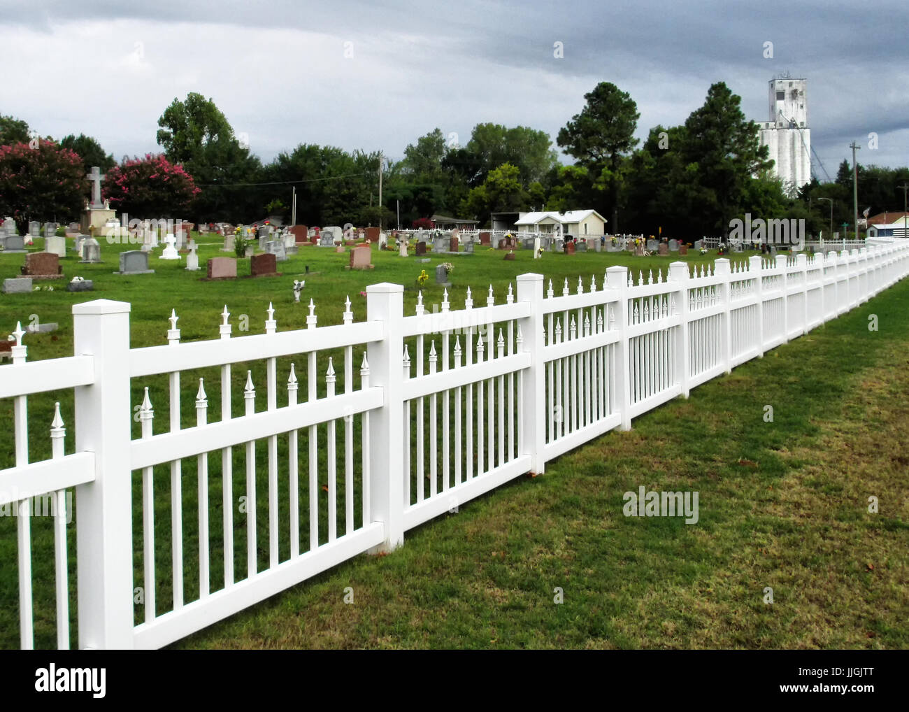 Une clôture s'étend le long de la Sainte Thérèse cimetière en Oklahoma avec Harrah élévateurs à grain en arrière-plan. Banque D'Images